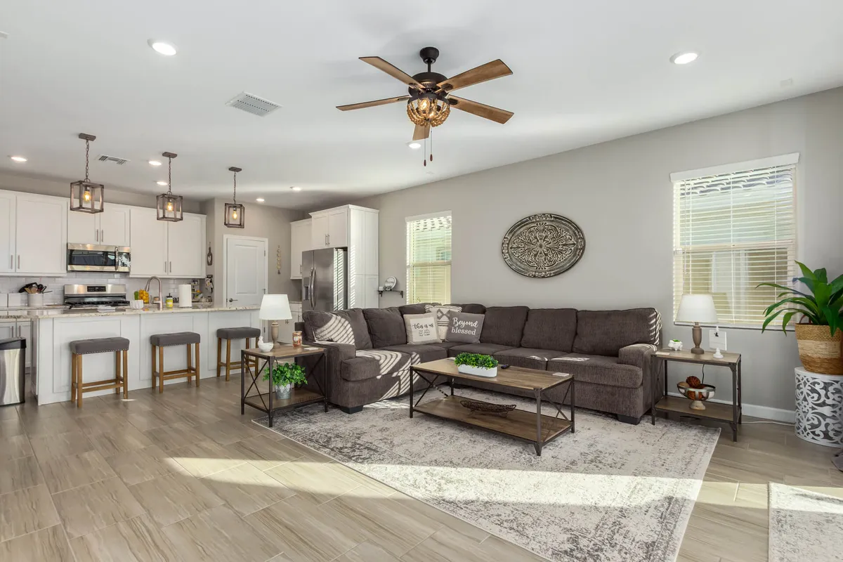 A cozy, open-plan living space combining a stylish sofa, a coffee table, and kitchen island. Tasteful wall art and welcoming lighting fixtures enhance the mood, while the layout encourages both relaxation and entertaining. The room feels modern and inviting, ideal for group activities after a day out.