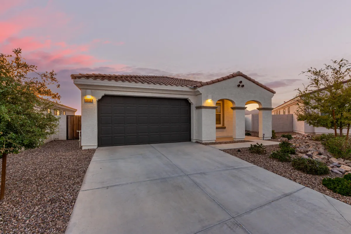 An inviting exterior view of the home's modern garage door and arched entryway, framed by a landscaped front yard and decorative roof tiles. The scene suggests an inviting welcome for families returning from days of adventure or neighborhood outings.